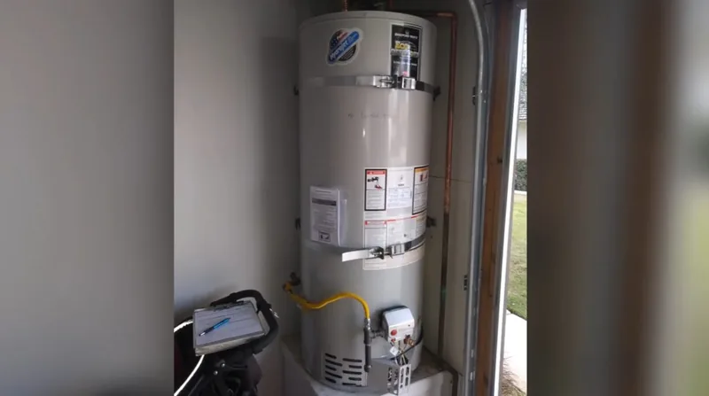 Gas tank water heater standing in a utility closet with a yellow gas connector, a clipboard and a notepad on a rolling cart